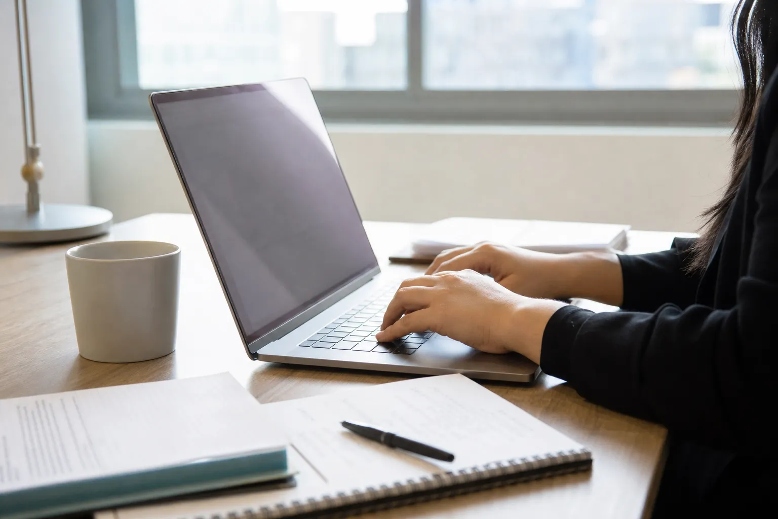 Personne rédigeant un e-mail professionnel sur un ordinateur portable, notes manuscrites à côté