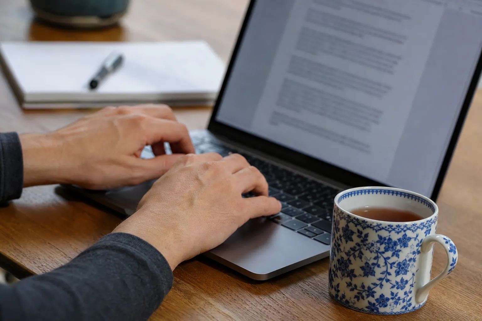 Mains tapant sur un clavier d’ordinateur portable avec un document ouvert à l’écran