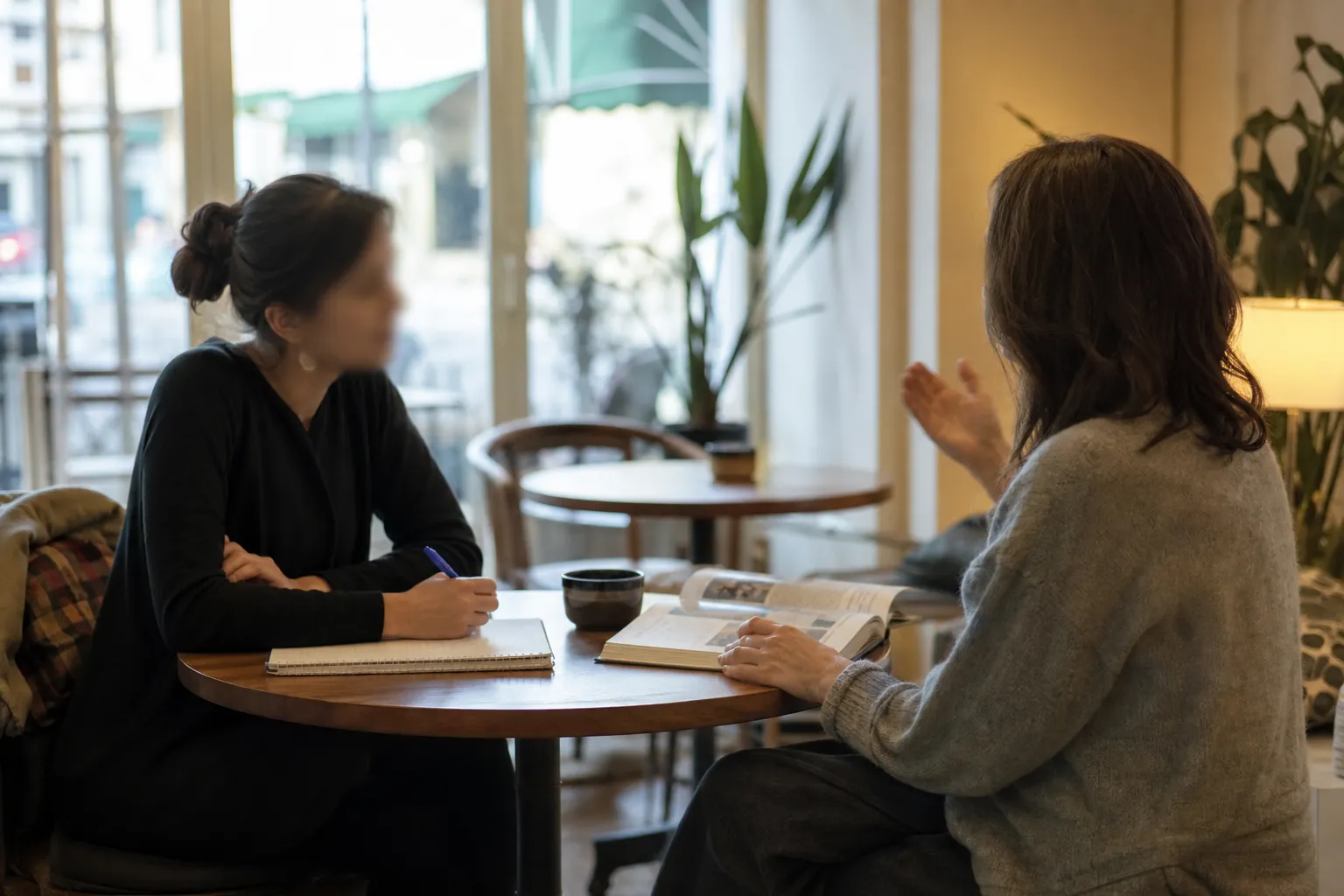 Cours particulier d’anglais pour adulte en présentiel, deux personnes assises face à face avec un carnet