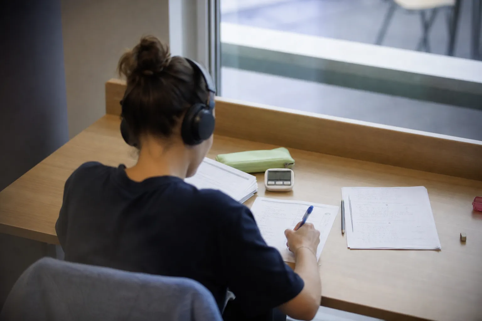 Personne s’entraînant sur un test chronométré avec casque audio et feuilles d’exercices